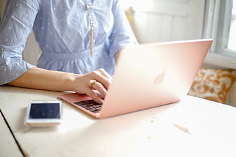 Woman Typing on Pink Laptop at White Desk