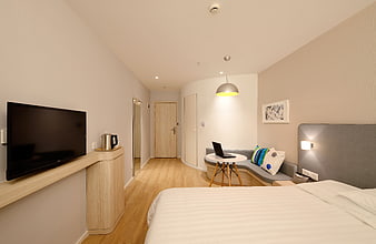 Modern hotel room interior with bed, desk, and TV