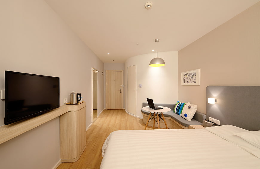 Modern hotel room interior with bed, desk, and TV