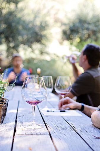 Outdoor Wine Tasting Session With Friends At A Rustic Wooden Table