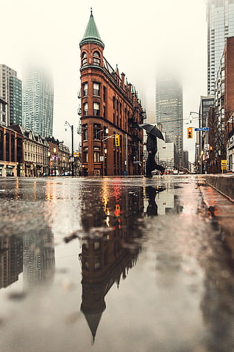 Low angle shot of pedestrian with umbrella on rainy city street