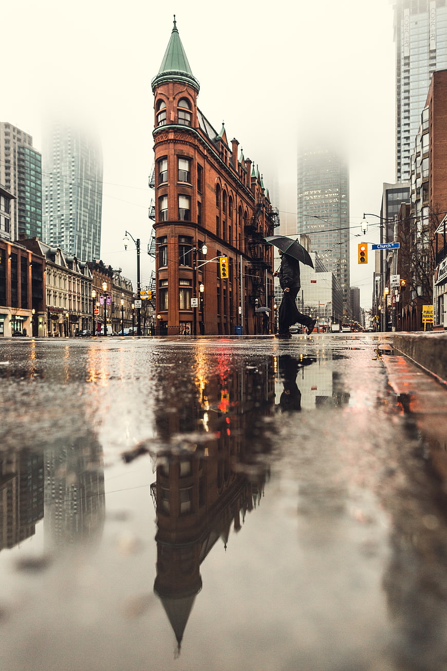 Low angle shot of pedestrian with umbrella on rainy city street