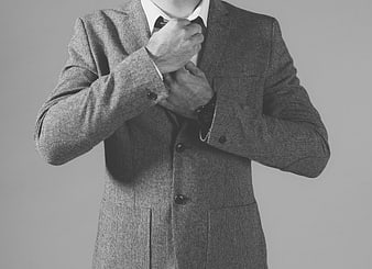 Man adjusting tie in gray wool suit jacket