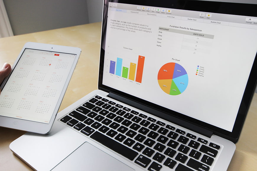 Laptop and tablet displaying business charts and calendar on desk