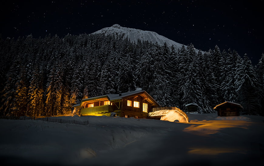 Cozy Alpine Chalet Under Starry Night Sky With Snowy Mountain