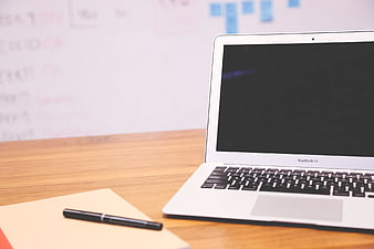White MacBook Air on Wooden Desk with Notebook and Pen