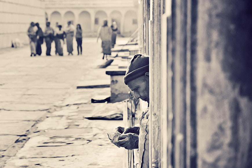 Sadhu monk counting money in Indian temple courtyard