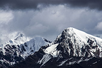 Dramatic Snow-Capped Mountain Peaks Under Stormy Clouds