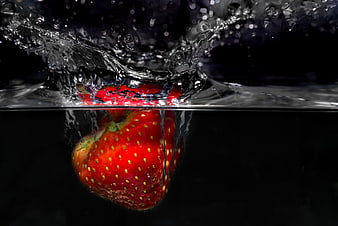 Fresh Strawberry Splashing into Water on Black Background