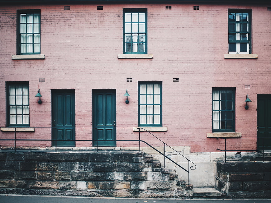 Pink brick building facade with teal doors and windows
