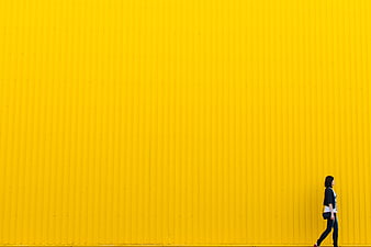 Woman Walking Past Vibrant Yellow Corrugated Wall