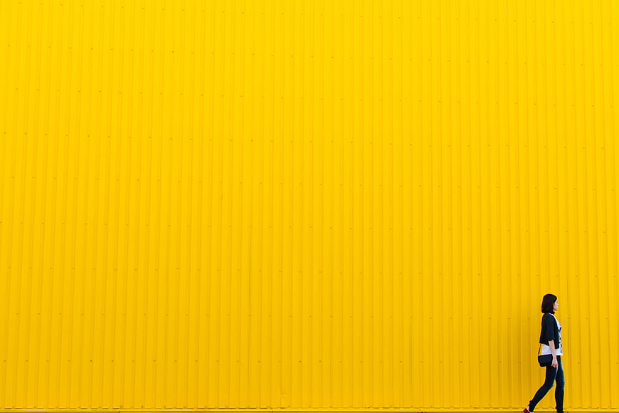 Woman Walking Past Vibrant Yellow Corrugated Wall