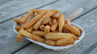 Salted French Fries in Paper Boat on Wooden Table