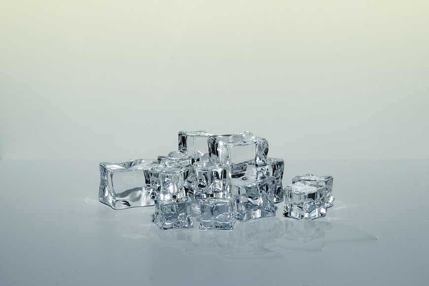 Stack of melting ice cubes on white background