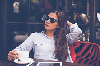 Stylish woman with sunglasses relaxing at cafe table