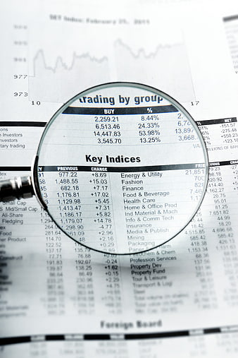 Magnifying glass examining financial stock market data on newspaper