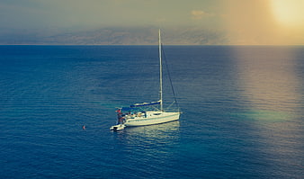 Aerial view of sailboat on blue sea with sunset