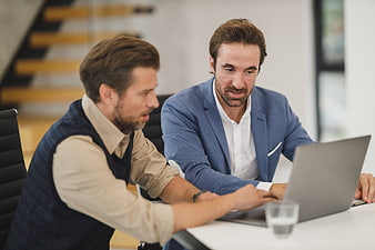 Two businessmen collaborating on a laptop in a modern office