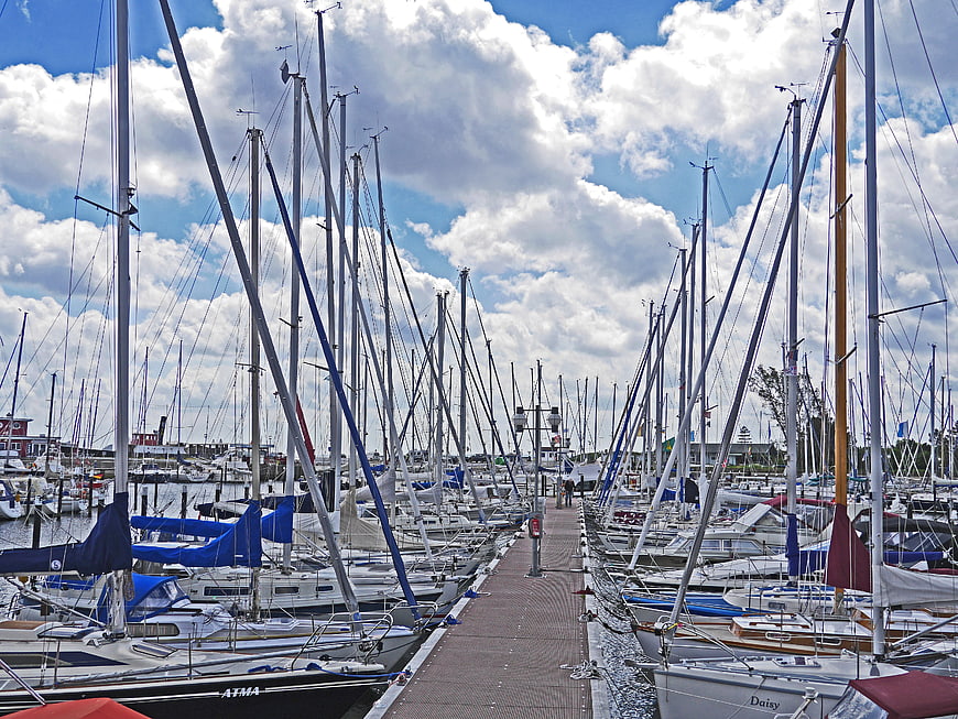 Sailboats docked in marina with blue sky and clouds