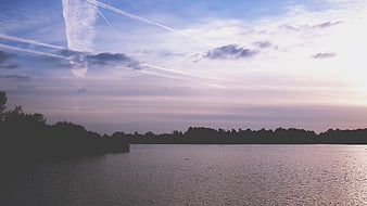 Serene Lake Sunset with Contrails and Tree Silhouette