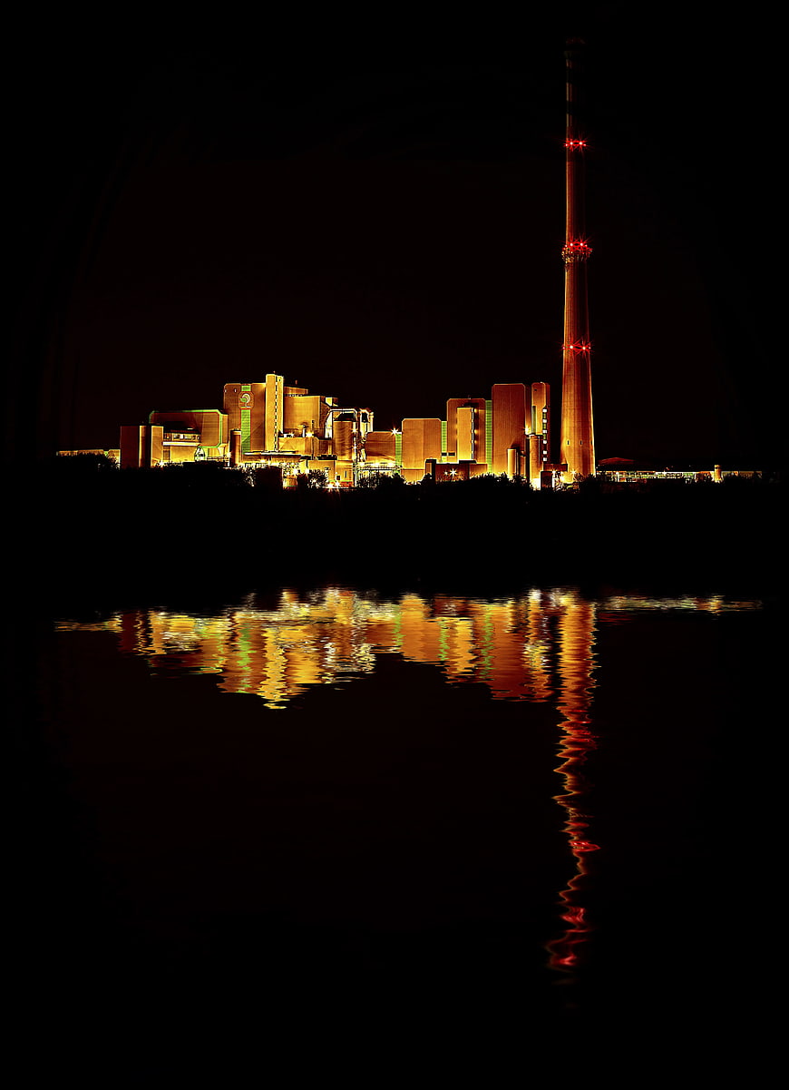 Illuminated Power Plant at Night with Water Reflection