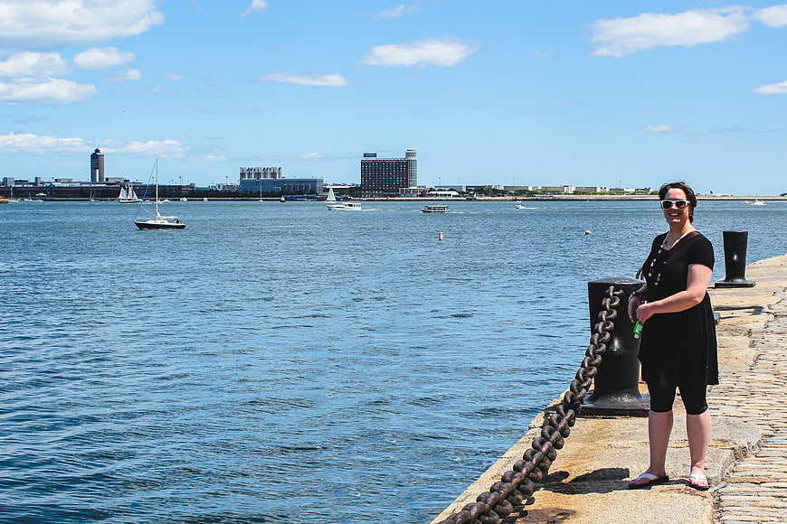 Woman standing on stone pier with harbor and city skyline background