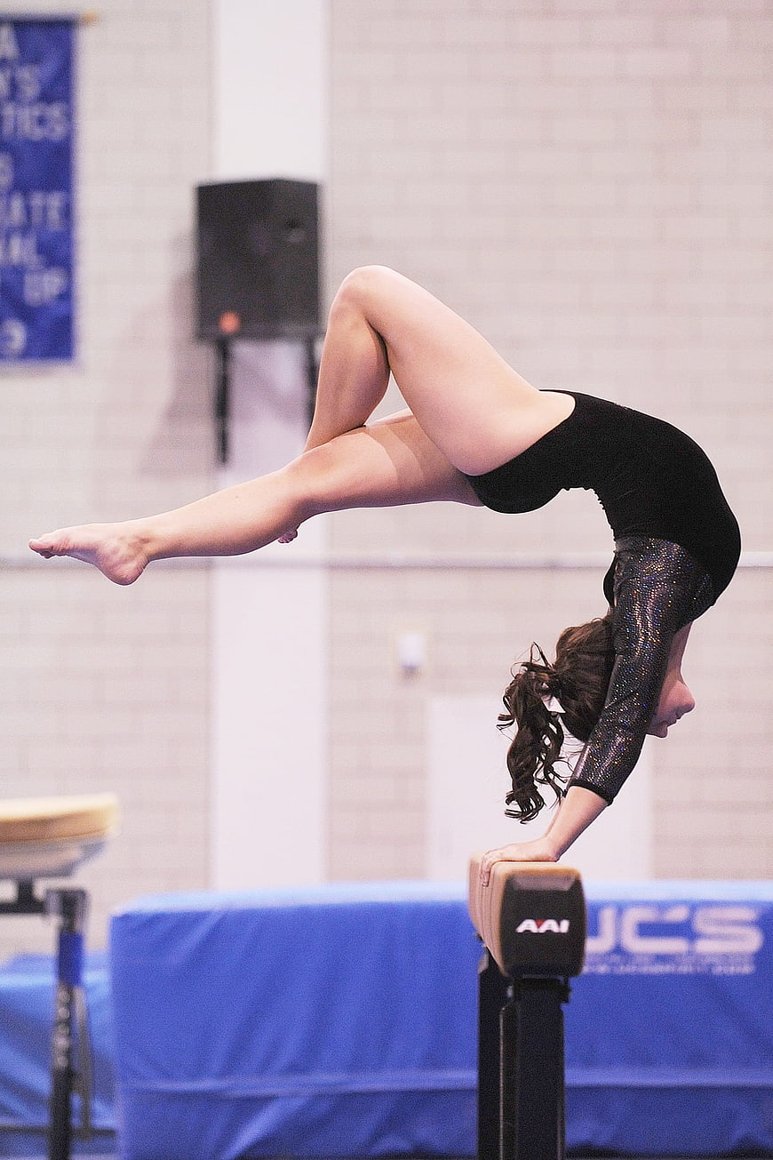Female gymnast performing handstand on balance beam