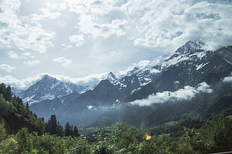 Majestic Snow-Capped Mountain Peaks with Clouds and Forest