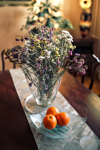 Dried flowers and oranges on a dining table runner
