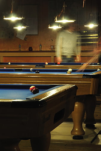 Motion blur of billiards players in a dimly lit pool hall