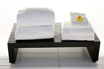 White towels on black bench with yellow rubber duck in bathroom