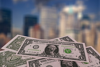 US One Dollar Bills Scattered Against Blurred City Skyline