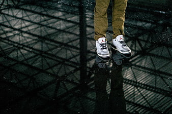 White sneakers with red logo on wet reflective floor