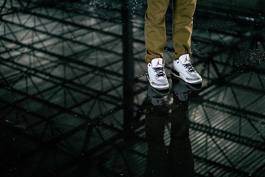 White sneakers with red logo on wet reflective floor