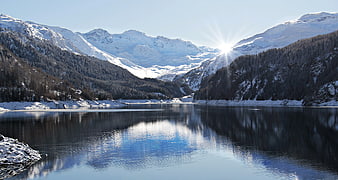 Snowy Alpine Lake with Mountain Reflections and Sunburst