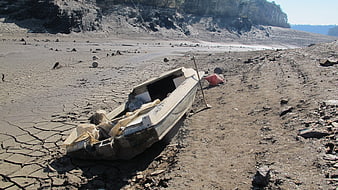 Abandoned boat on cracked dry lakebed during drought