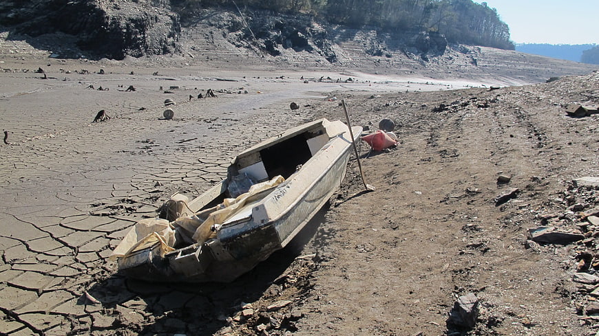 Abandoned boat on cracked dry lakebed during drought