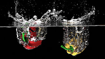 Red and yellow bell peppers splashing into water