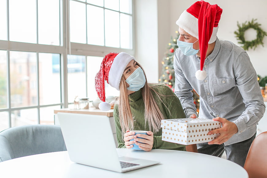 Couple in Santa Hats and Face Masks Celebrating Christmas with Gift