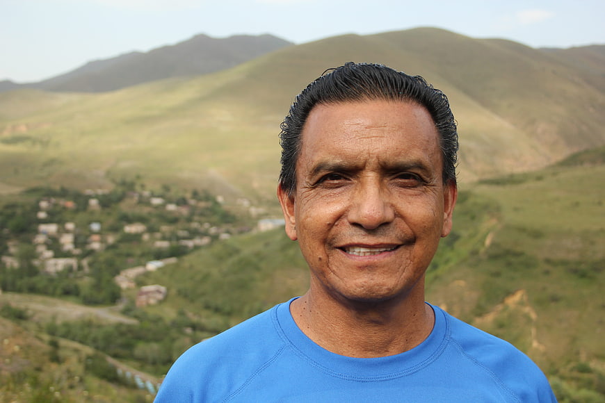 Smiling Senior Man Portrait Against Green Mountain Landscape