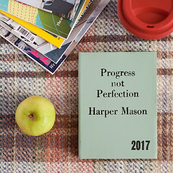 Flat lay of journal, apple, and coffee on textured rug