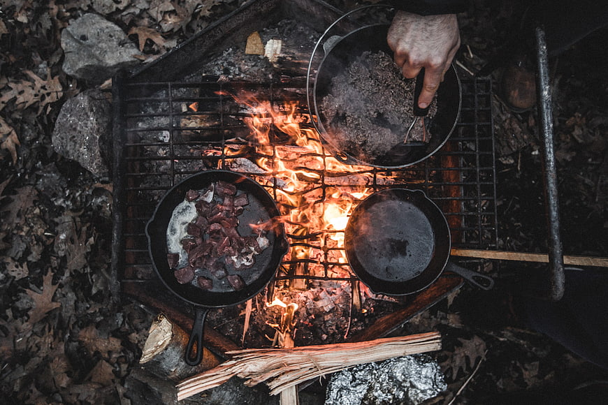 Top view of cast iron skillets cooking over campfire