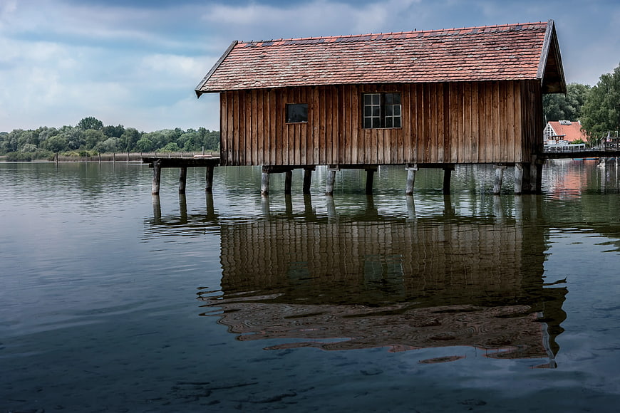 Rustic wooden house on stilts over calm river water
