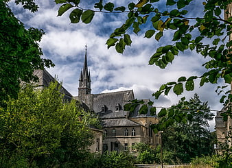 Historic Gothic Church Tower Framed By Lush Green Foliage