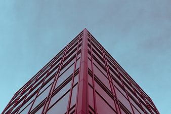 Low angle view of red modern skyscraper against blue sky