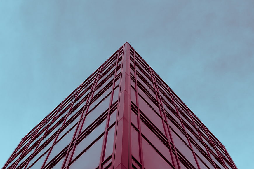 Low angle view of red modern skyscraper against blue sky