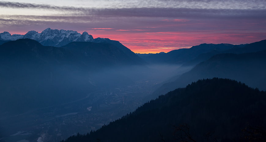 Dramatic mountain sunset with pink sky and misty valley