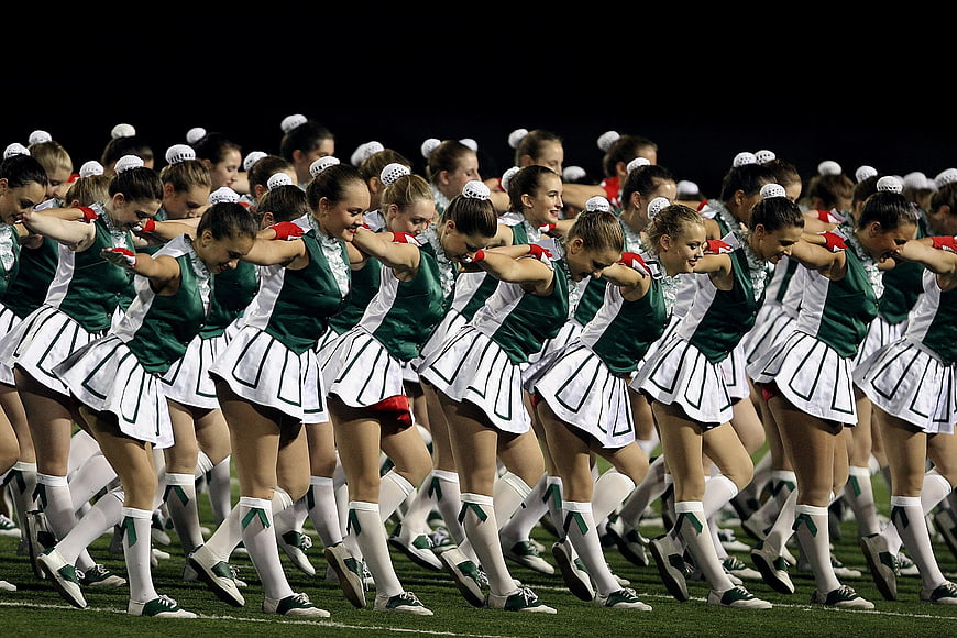Cheerleaders in Green and White Uniforms Performing on Field
