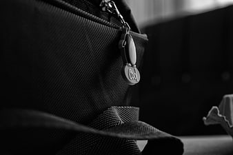 Close-up of black bag zipper with 'Cool' charm in black and white