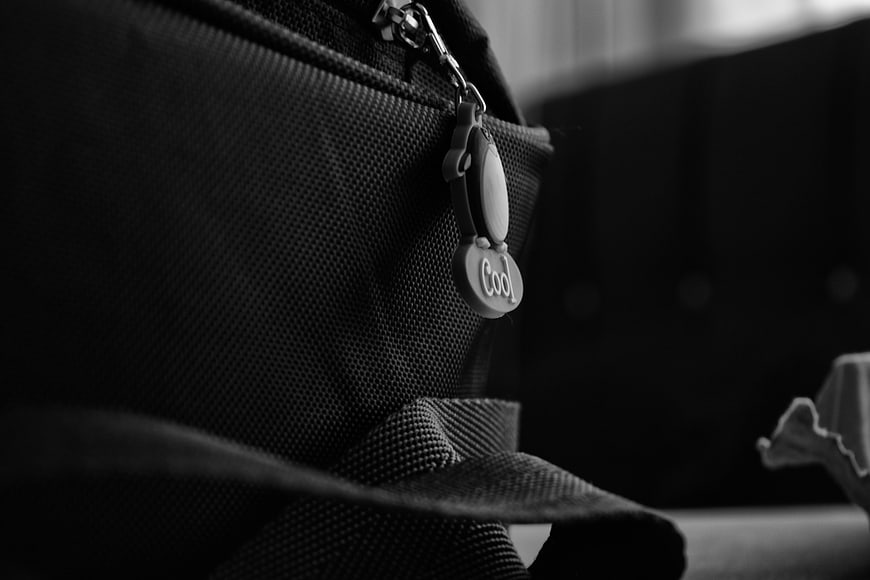 Close-up of black bag zipper with 'Cool' charm in black and white